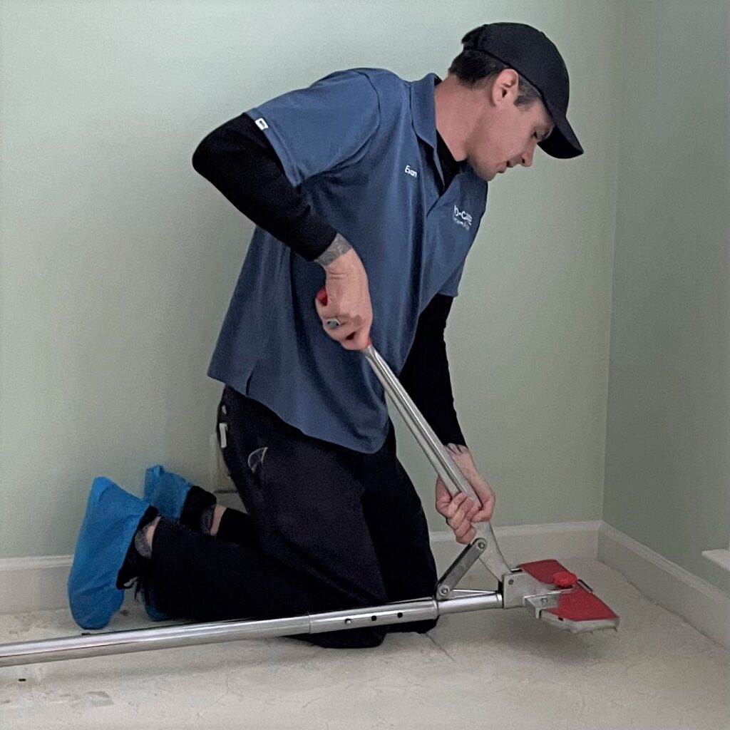 Professionals use specialized tools.  This technician in shown using a pole stretcher to repair carpet rippling.
