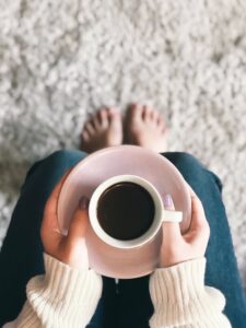 Foreground shows person holding coffee over rug