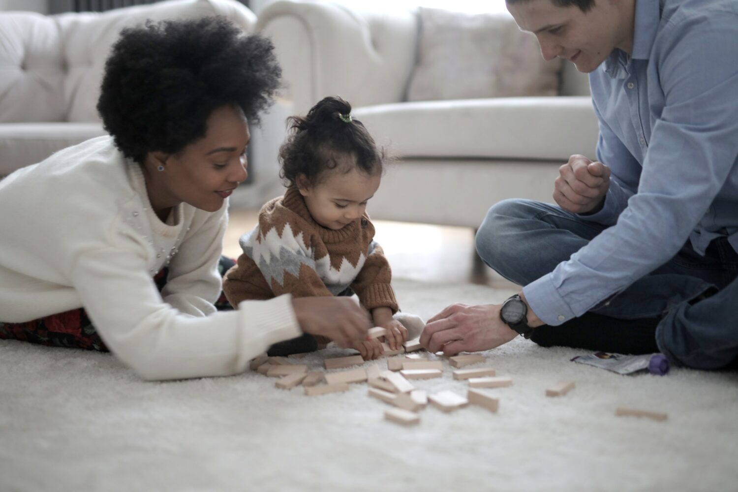 Family plays with blocks on light carpet