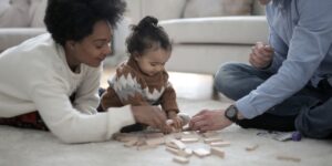 Family plays with blocks on light carpet