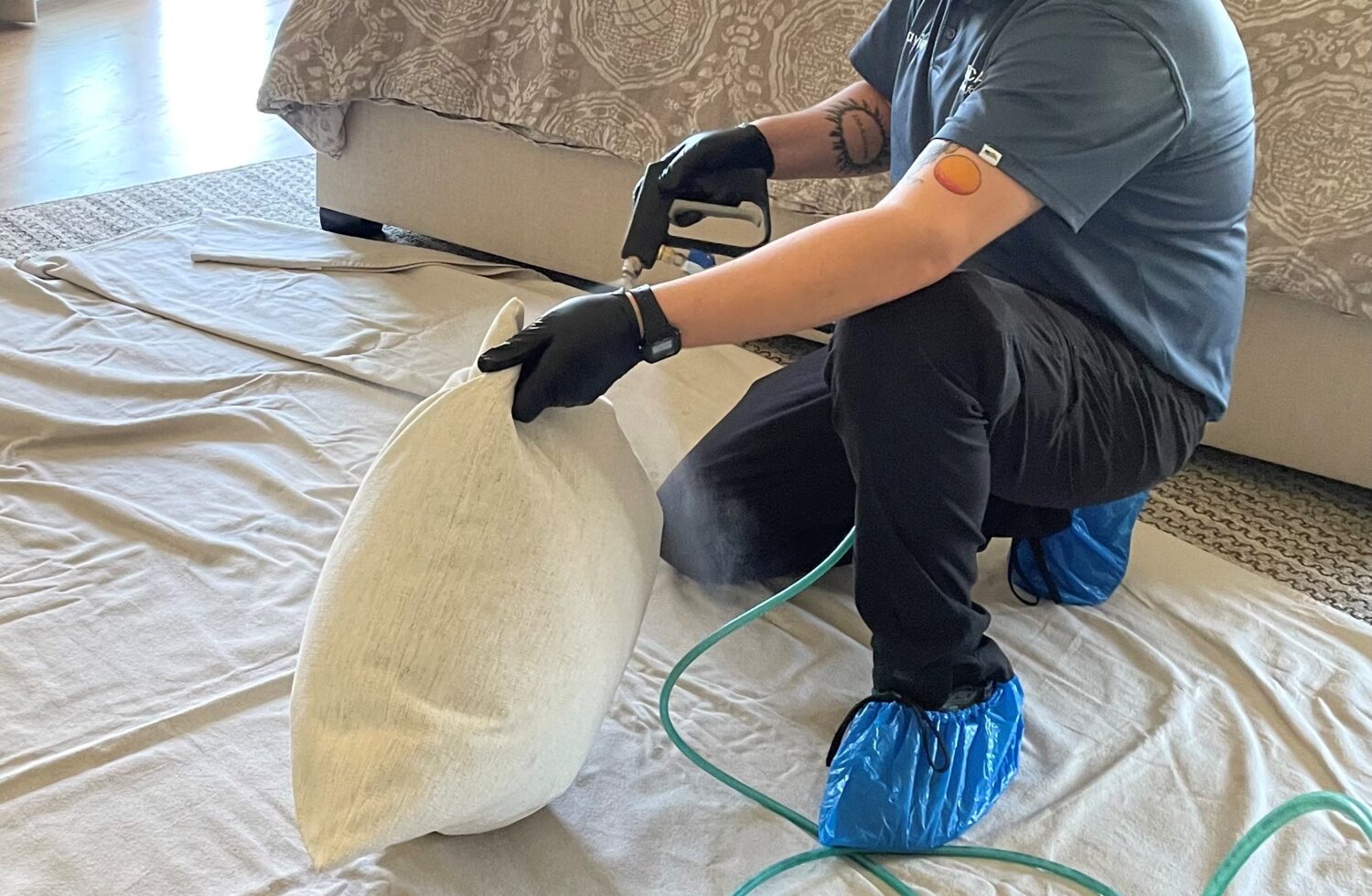 Technician applies fabric protection to a white cushion.