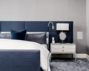 Blue upholstered headboard and silver carpet in modern bedroom.