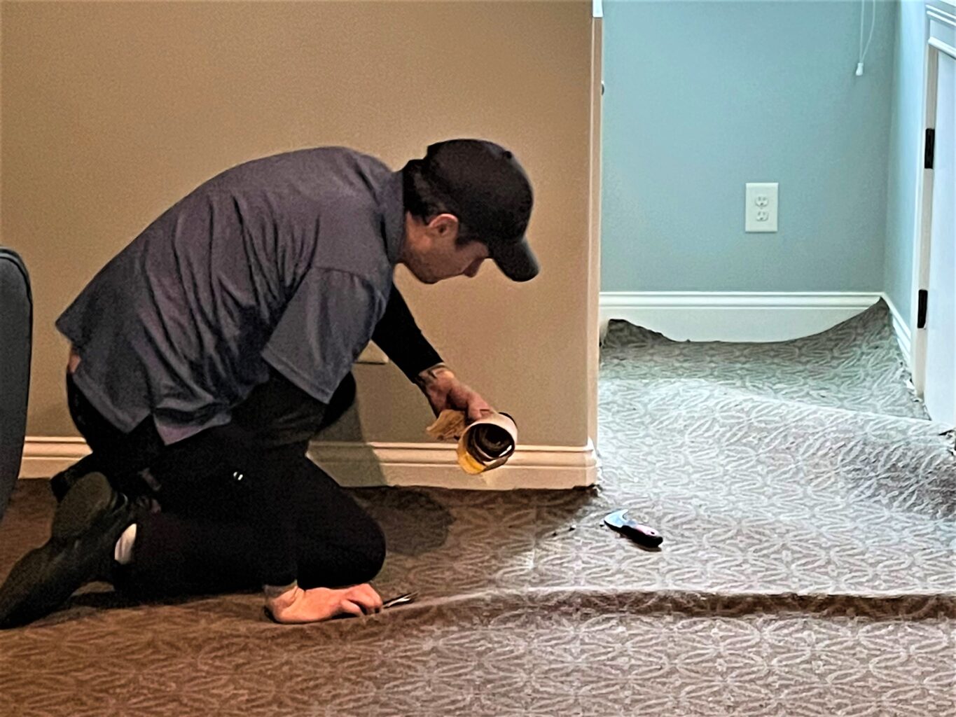 Technician pulls carpet free of wall to stretch.