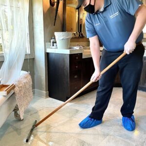 Technician seals marble flooring in primary bath.