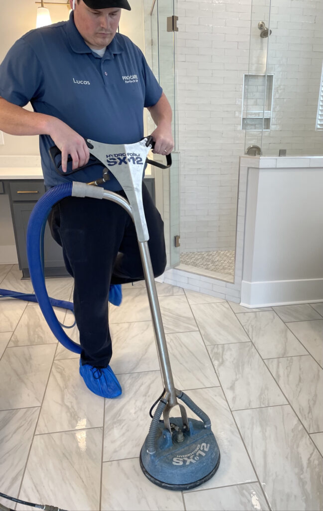 Professional cleans tile floor in bathroom with commercial-grade tool.
