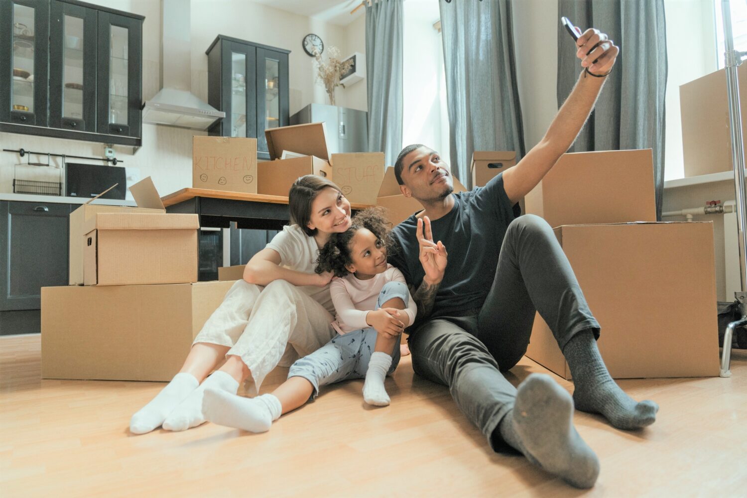 Family poses for selfie among moving boxes.