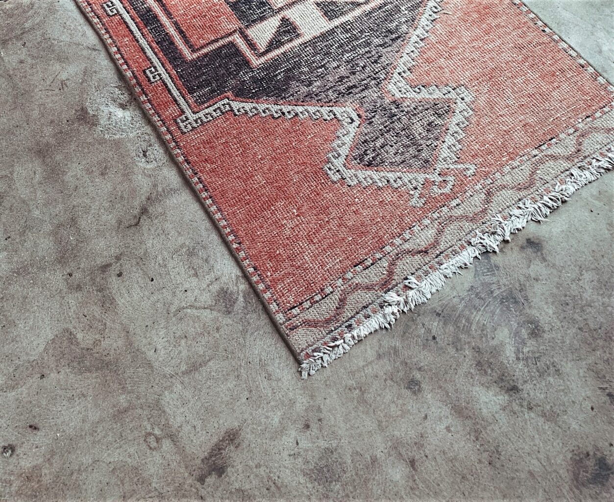Tribal rug is rolled out on concrete floor.