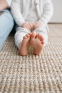 Child sits on woven natural rug.