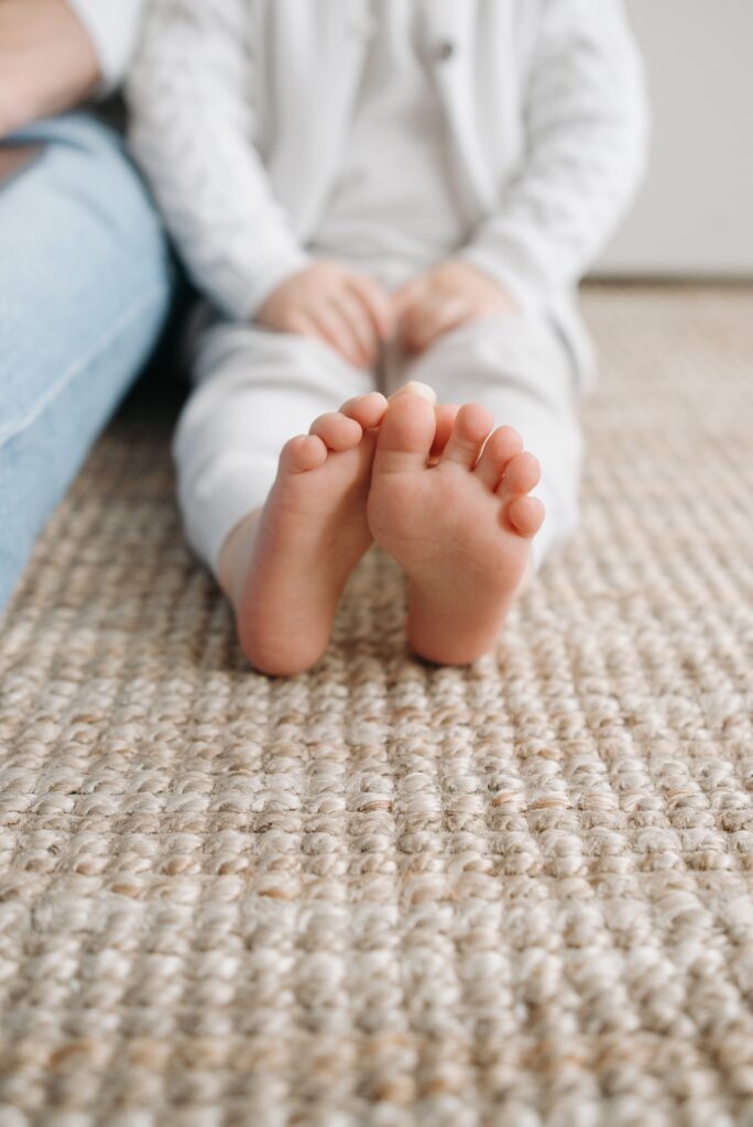 One top ten rug trend is the use of natural and sustainable area rugs. Child sits on woven natural rug.