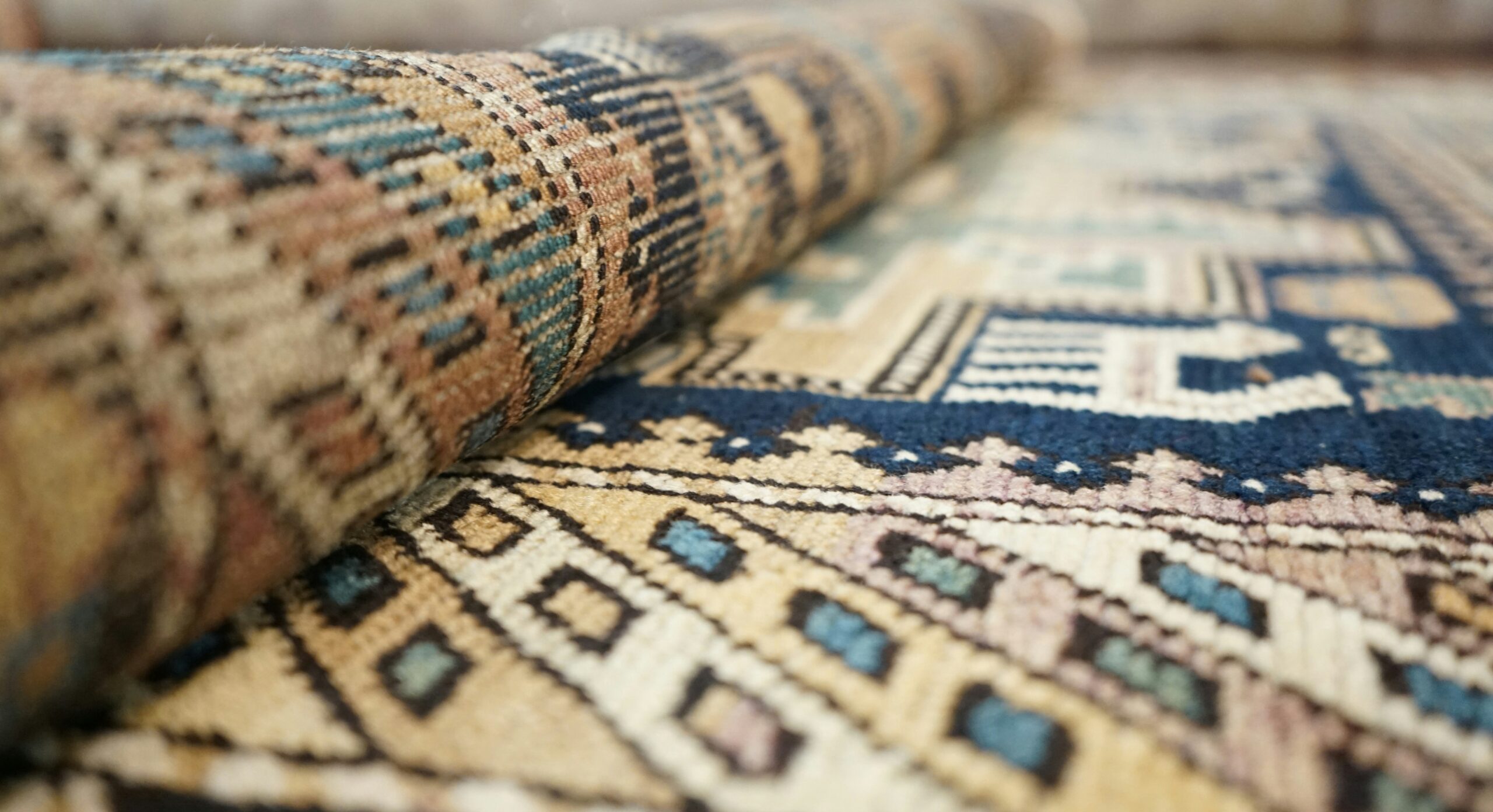 Gold and blue oriental rug partially unrolled.